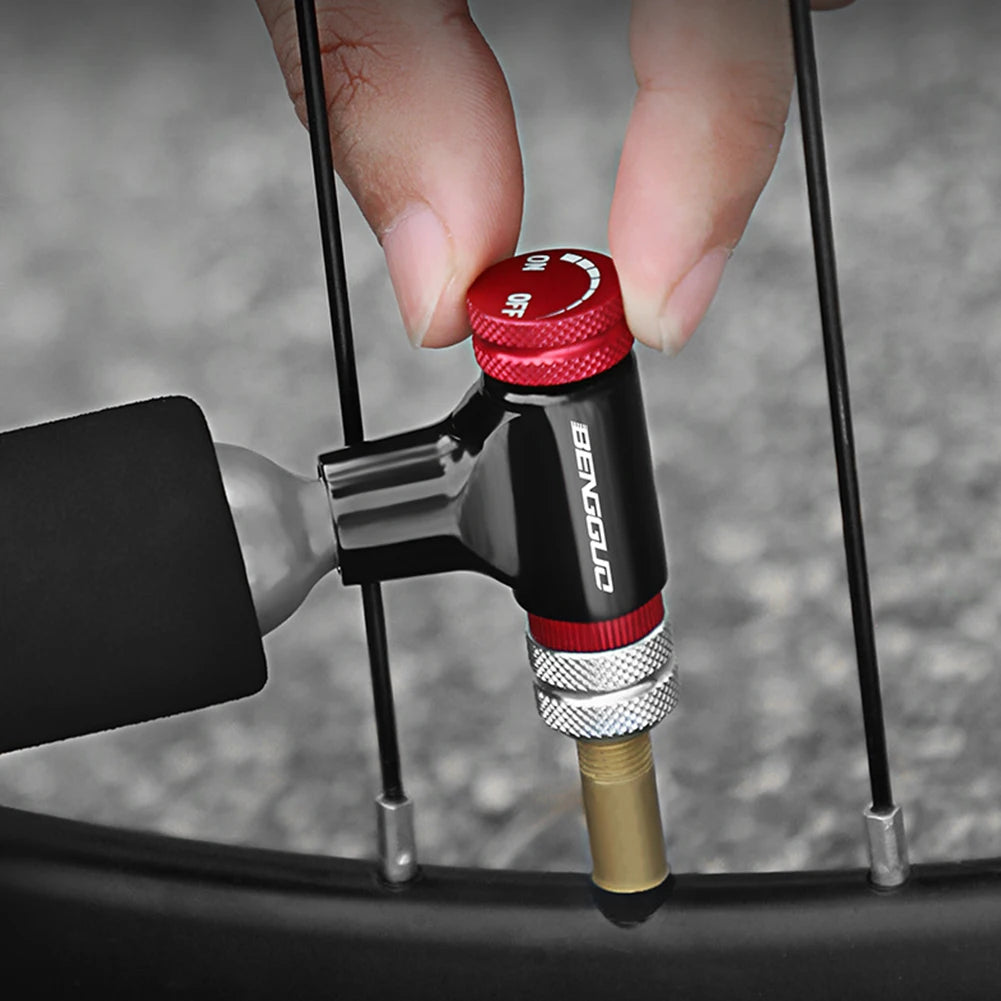 Hand using a bicycle pump with a red and black handle on a blurred background