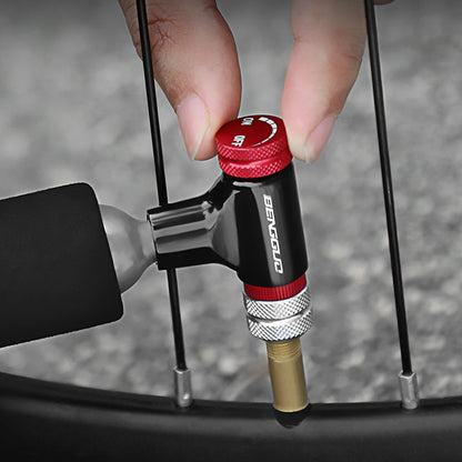 Hand using a bicycle pump with a red and black handle on a blurred background