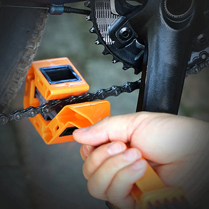 Person using an orange chain tool on a bicycle chain