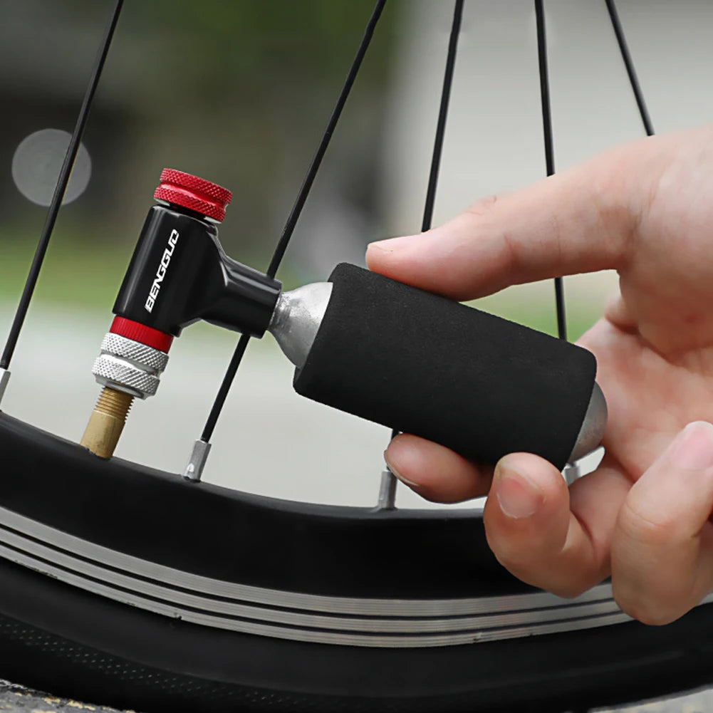Hand using a bicycle pump to inflate a tire with a blurred outdoor background