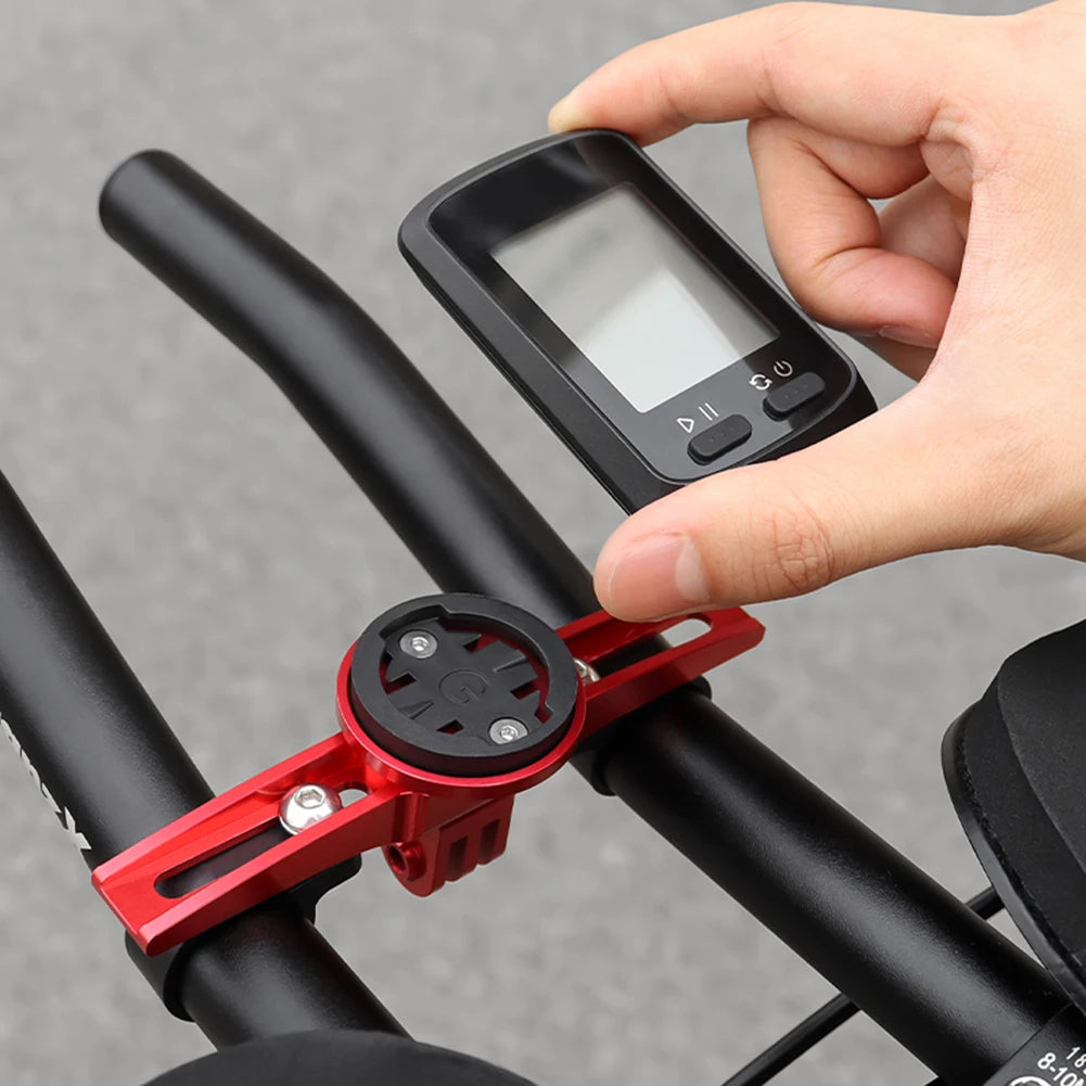 Hand holding a GPS device attached to a bicycle handlebar with a red mount.