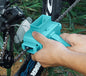 Person using a turquoise chain tool on a bicycle chain with grass in the background