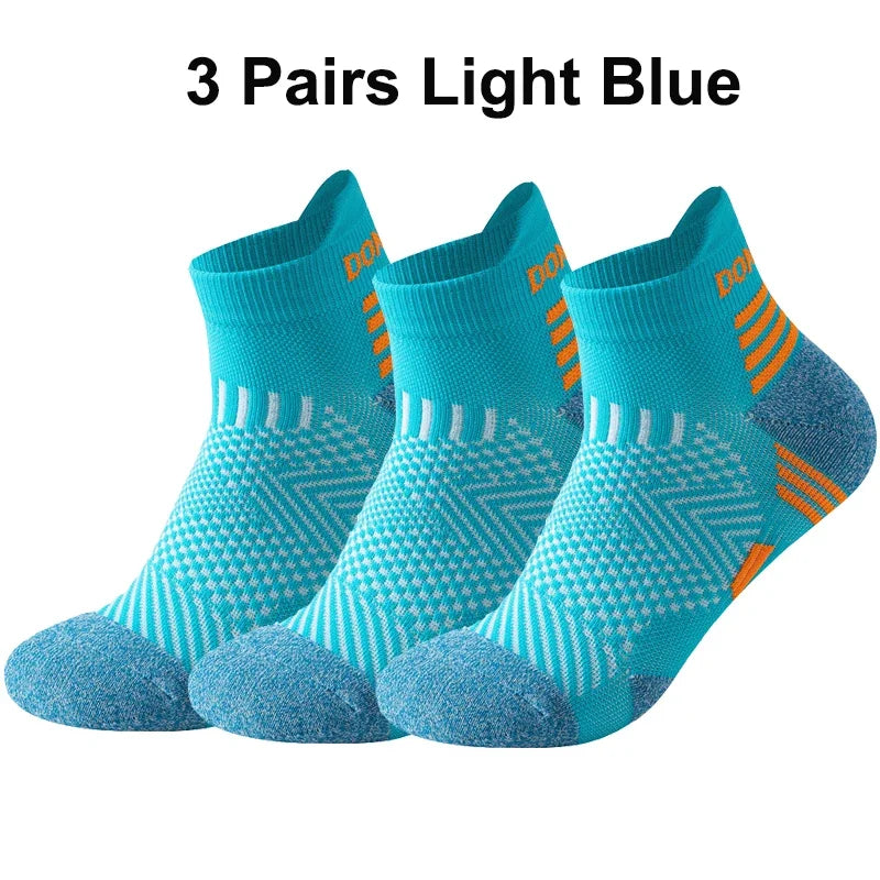 Three pairs of light blue running socks with orange accents on a white background
