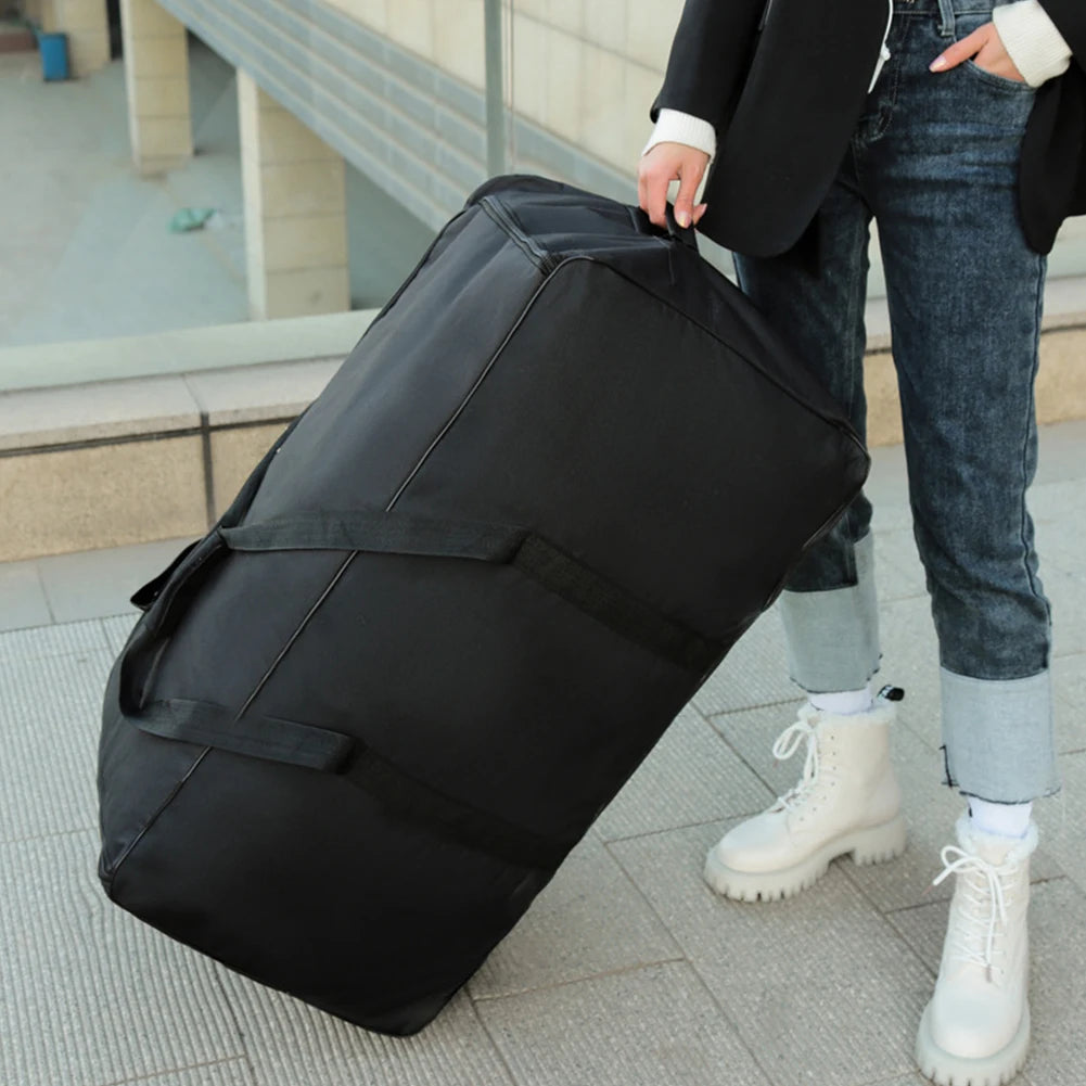 Person holding a large black duffel bag outdoors.