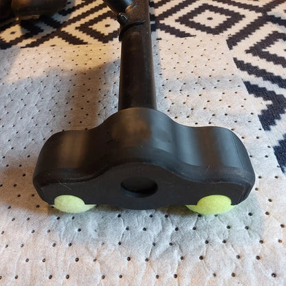 Black dog toy with green ends on a textured surface