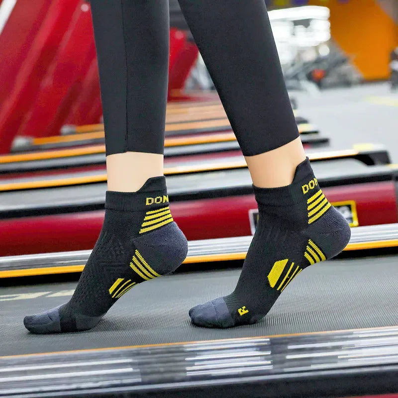 Person wearing black running socks with yellow accents on a treadmill.