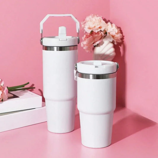 Two white tumblers with silver lids on a pink background with flowers and books.