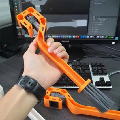 Person holding an orange chain cleaning tool with a computer setup in the background