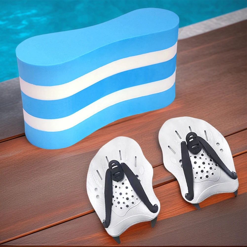 Two white swim hand paddles with black straps on a wooden surface, with a blue pool float in the background.