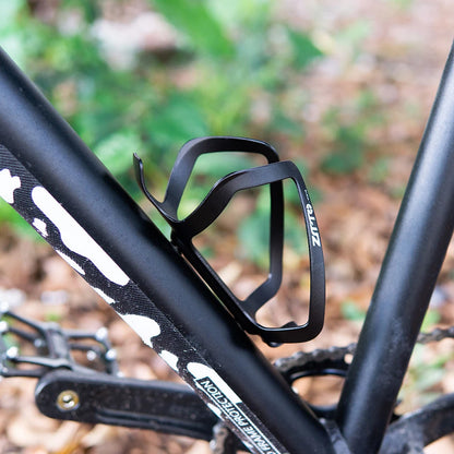 Black bicycle water bottle holder on a bike frame with a blurred natural background